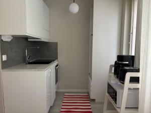a kitchen with white cabinets and a red and white rug at Cozy apartment for 2 - free parking in Oulu