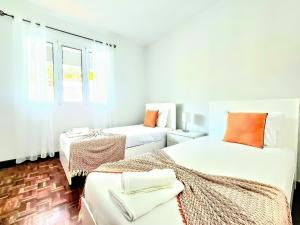 ein weißes Zimmer mit zwei Betten und einem Fenster in der Unterkunft Villa Herédia in Ribeira Brava + 15 Fotos