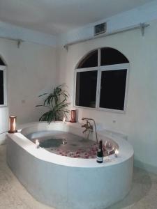 迪亚尼海滩Romantic Double Room at Villa Paradise的一个宽敞的白色房间，里面有个浴缸，浴缸里放着一瓶香槟。
