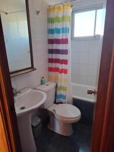 a bathroom with a toilet and a sink and a shower curtain at Cabaña para 6 personas cerca de la playa in Coquimbo