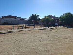a dirt field with palm trees and a fence at Cabaña para 6 personas cerca de la playa in Coquimbo