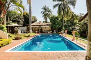 a swimming pool in front of a house with palm trees at Quinta San Francisco in Cuernavaca