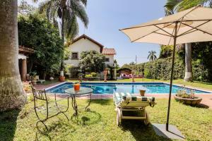 an umbrella and chairs and a table and a pool at Quinta San Francisco in Cuernavaca
