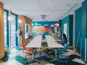 a cafeteria with tables and chairs and a mural at ibis Styles Warszawa Centrum in Warsaw