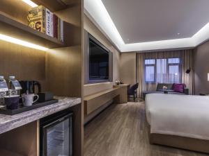 閔行にあるMercure Shanghai Jiutingのベッドと机があるホテルの部屋