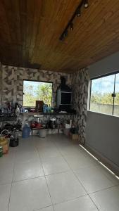 a room with a stone wall and a kitchen with a window at Recanto das Guerreiras in Marau