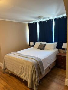 a bedroom with a large bed with blue curtains at Midstream Manor Unit 8 - 2 Bedroom Apartment in St. John's