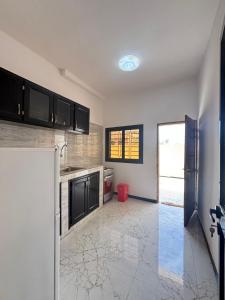 a kitchen with black cabinets and a refrigerator at Immeuble Sali Laye in Darou Rhamane