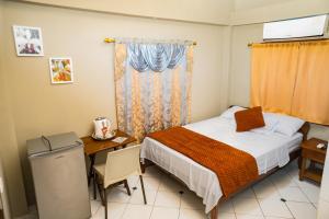 a small bedroom with a bed and a desk and a table at La Casa Naranja Hostal in Olón