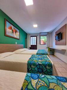 ein Hotelzimmer mit zwei Betten und einem Flachbildfernseher in der Unterkunft Pousada Casamar in Porto De Galinhas