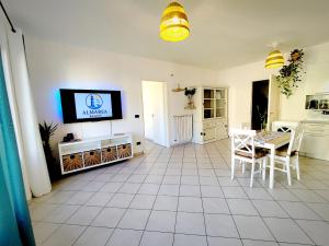 a living room with a table and a tv at Almarea Beach - Essenza del mare, calore di casa in Imperia