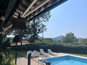 ein Swimmingpool mit weißen Stühlen und eine Terrasse mit Sitzgelegenheiten in der Unterkunft Villa Berhartia in Cambo-les-Bains