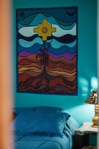 a painting of a cross hanging above a bed at Los Airampos in Humahuaca