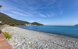 a rocky beach next to the ocean on a sunny day at Melodia Pension in Geoje 