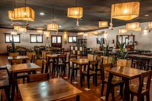 Un restaurante con mesas y sillas de madera y lámparas de araña. en Hotel Pastos Chicos, en Susques