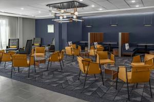 a waiting room with tables and chairs in a lobby at Courtyard by Marriott Sherman in Sherman