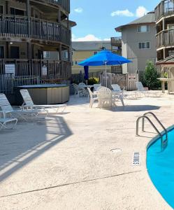 a patio with chairs and an umbrella and a pool at Salty Sisters in Kill Devil Hills