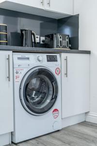 a white washing machine under a counter in a kitchen at Boddam getaway - CMC Stays in Boddam