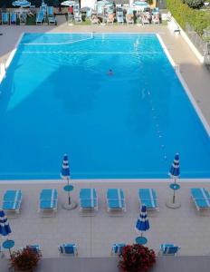 a large swimming pool with blue chairs and umbrellas at Almarea Beach - Essenza del mare, calore di casa in Imperia
