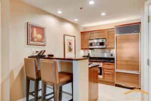 拉斯维加斯MGM Signature-33-714 1BR 2-Bath Balcony Suite的一间带木制橱柜的厨房和一间带凳子的酒吧