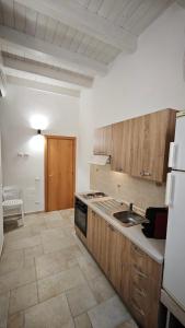 a kitchen with wooden cabinets and a sink and a refrigerator at ''B&B Santa Rita Corato fitta camere'' in Corato