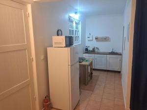 a kitchen with a microwave on top of a refrigerator at Studio Kerbignon, Piscine privée in Case-Pilote