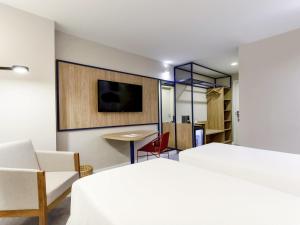 a bedroom with a bed and a desk and a tv at Novotel Salvador Rio Vermelho in Salvador +94 photos