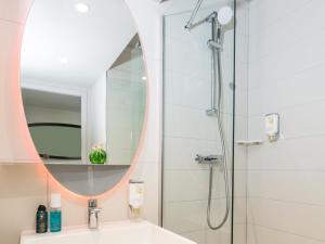 a bathroom with a shower and a sink and a mirror at Aparthotel Adagio access Palaiseau Saclay in Palaiseau +63 photos