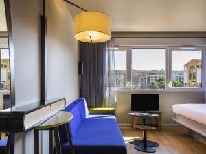 a hotel room with a blue couch and a bed at Aparthotel Adagio access Montpellier Centre in Montpellier