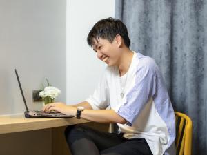 a young man sitting at a desk with a laptop at ibis Styles Bangkok Ratchada in Bangkok