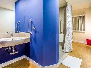 a blue bathroom with a sink and a shower at Ibis Budget Uberlândia in Uberlândia +81 photos