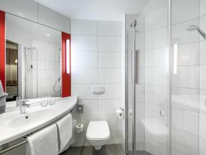 a bathroom with a toilet and a sink and a shower at ibis Landshut City in Landshut +58 photos