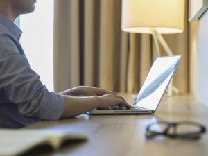 サンティアゴにあるPullman Santiago Vitacuraの机に座ってノートパソコンを使っている人