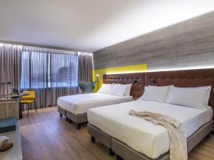 una camera d'albergo con due letti e una scrivania di Pullman Santiago El Bosque a Santiago