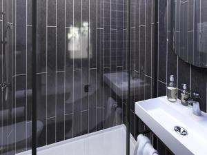 a black tiled bathroom with a sink and a toilet at Ibis Marseille Centre Prefecture in Marseille