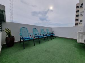 eine Reihe blauer Stühle auf einem Balkon in der Unterkunft APART -Hotel 2 habitaciones compartidas con baños privado in Vila El Carmen