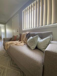 eine Couch mit Kissen darauf in einem Wohnzimmer in der Unterkunft Ella Cottage - Relaxing romantic escape-Southern Highlands 
