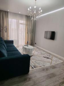 Una sala de estar con un sofá azul y una lámpara de araña. en 24 home актау, en Aktau