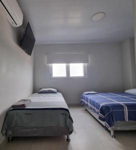ein Schlafzimmer mit zwei Betten und einem Flachbildfernseher in der Unterkunft APART -Hotel 2 habitaciones compartidas con baños privado in Vila El Carmen