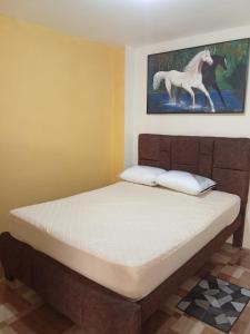 a bed in a room with a painting of a horse at Entire apartment in Ambato Ficoa in Ambato
