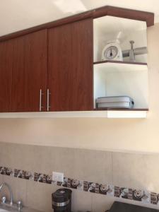 a kitchen with wooden cabinets and a clock on the wall at Entire apartment in Ambato Ficoa in Ambato +6 photos