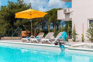a group of chairs and an umbrella next to a swimming pool at Haus Quadro in Rabac