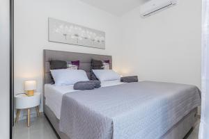 a white bedroom with two beds and a table at Haus Quadro in Rabac +2 photos