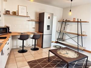 Una cocina con una mesa y dos taburetes y un refrigerador. en L'Ancien Moulin du Grand Annecy, en Annecy