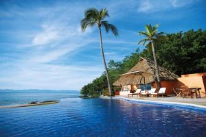 a pool at a resort with palm trees and the ocean at Luxury Villa Paloma Blanca in Cruz de Huanacaxtle