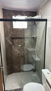 a glass shower in a bathroom with a toilet at Minha house in Navegantes