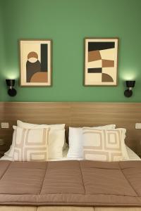 ein Schlafzimmer mit einem Bett mit zwei Bildern an der Wand in der Unterkunft Hotel Aurelia Milano Centrale in Mailand