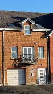 ein Backsteingebäude mit Balkon und Garage in der Unterkunft Luxury Portrush Holiday Homes - The Glynn, Portrush Sleeps 12 - 5 bedrooms in Portrush