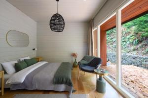 a bedroom with a bed and a chair and a window at 4 Strony Lasu in Gołaczów