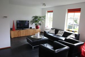 スコールルにあるVakantiehuis Zeeduinenbosのリビングルーム(黒革の家具、薄型テレビ付)